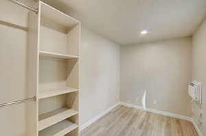 Laundry room featuring light wood finished floors, a wall mounted AC, a textured ceiling, and recessed lighting