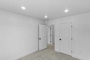 Unfurnished bedroom with light carpet and recessed lighting