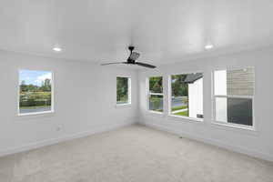 Spare room featuring plenty of natural light, light carpet, and ceiling fan