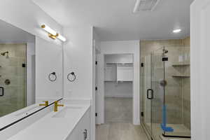 Bathroom with a spacious closet, vanity, a shower stall, light tile patterned floors, and recessed lighting