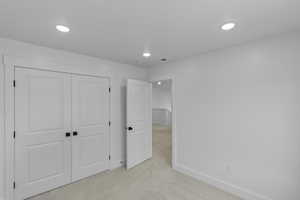 Unfurnished bedroom with light colored carpet, a closet, and recessed lighting