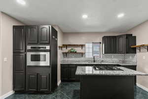 Kitchen with open shelves, stainless steel appliances, a kitchen island, decorative backsplash, and recessed lighting