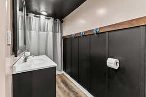 Bathroom with curtained shower, vanity, and wood finished floors