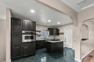 Kitchen featuring open shelves, oven, decorative backsplash, a center island, and recessed lighting