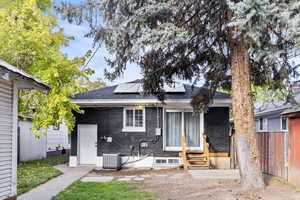 Back of house featuring brick siding, solar panels, and roof with shingles
