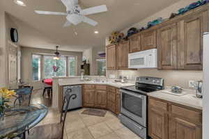 Kitchen featuring stainless steel appliances, a peninsula, light countertops, recessed lighting, and brown cabinetry