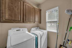 Laundry room featuring independent washer and dryer and cabinet space