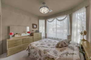 Bedroom with light carpet and a chandelier
