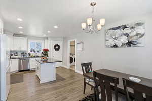 Kitchen with white cabinetry, pendant lighting, a center island, dishwasher, and light wood-style floors