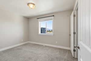 Spare room featuring light colored carpet and baseboards