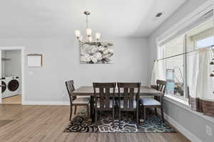 Dining space featuring a chandelier, light wood-type flooring, and washer and dryer