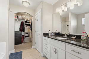 Full bathroom with vanity, a shower stall, and a walk in closet