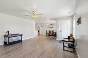 Living area with light wood-style floors, a chandelier, and a ceiling fan