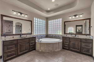 Full bath with a garden tub, two vanities, a tray ceiling, a shower stall, and recessed lighting