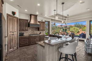Kitchen featuring pendant lighting, a center island with sink, recessed lighting, a kitchen bar, and decorative backsplash