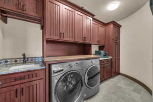 Laundry room featuring cabinet space, stone tile floors, and washing machine and dryer
