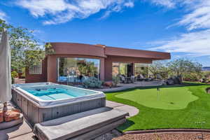 View of patio / terrace with a putting green and a hot tub