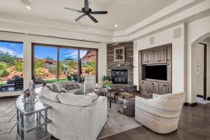 Living room featuring stone tile floors, arched walkways, a fireplace, recessed lighting, and a ceiling fan