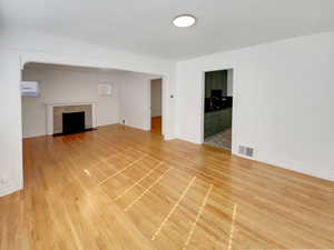 Unfurnished living room with light wood-type flooring and a tiled fireplace