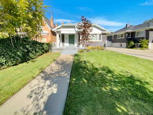 Bungalow-style home featuring a porch, brick siding, and a front yard