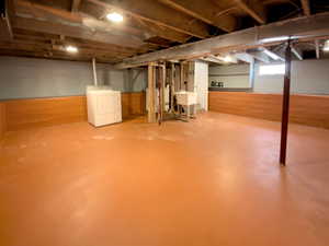Below grade area featuring washer / clothes dryer, wood walls, and a wainscoted wall