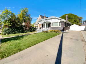 Bungalow-style home with brick siding, a porch, a chimney, and a gate