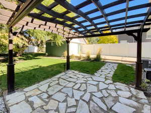 Fenced backyard featuring a pergola, a patio, and an outbuilding