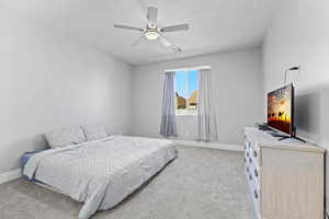 Carpeted bedroom with a ceiling fan and baseboards