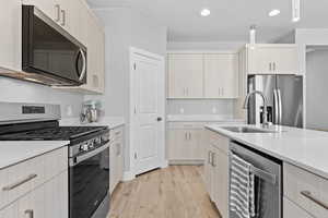 Kitchen featuring stainless steel appliances, light wood-style floors, hanging light fixtures, recessed lighting, and light stone countertops
