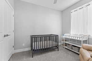 Bedroom featuring a crib, carpet, and a ceiling fan