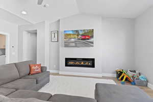 Living room featuring wood finished floors, a glass covered fireplace, ceiling fan, washer / clothes dryer, and recessed lighting
