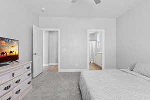 Bedroom with light carpet, ceiling fan, and ensuite bath
