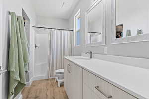 Full bathroom with curtained shower, light wood-type flooring, and vanity
