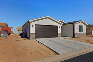 Single story home featuring stone siding, stucco siding, driveway, and an attached garage