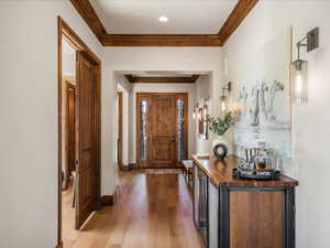 Entryway with light wood-type flooring, ornamental molding, and wine cooler