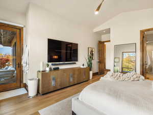 Bedroom featuring vaulted ceiling, access to exterior, and light wood-type flooring