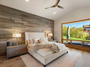 Bedroom with wooden walls, lofted ceiling, light wood finished floors, recessed lighting, and a ceiling fan
