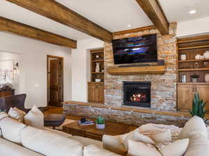 Living area featuring beam ceiling, built in shelves, wood finished floors, a fireplace, and recessed lighting