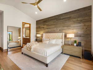 Bedroom featuring wood walls, light wood-style flooring, vaulted ceiling, a ceiling fan, and recessed lighting