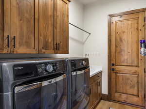Washroom featuring light wood-style flooring, cabinet space, and separate washer and dryer