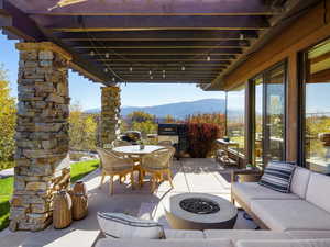 View of patio with a mountain view, outdoor dining area, and an outdoor living space with a fire pit
