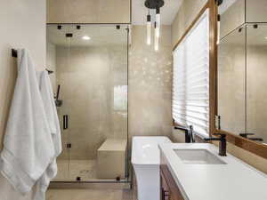 Bathroom with vanity, a soaking tub, a stall shower, and tile walls