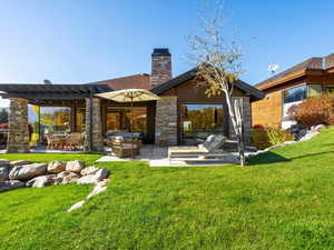 Rear view of property featuring a patio area, a lawn, a pergola, and a chimney