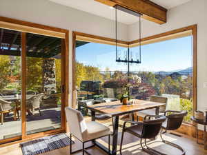 Dining area with wood finished floors, a chandelier, and beamed ceiling