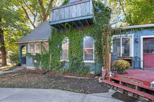 View of front of property with roof with shingles, stucco siding, and a wooden deck