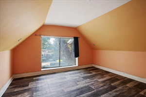 Bonus room with lofted ceiling and dark wood finished floors