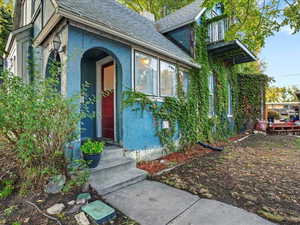 Entrance to property featuring a shingled roof, a chimney, and stucco siding