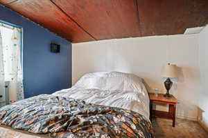 Carpeted bedroom with wooden ceiling and vaulted ceiling