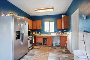Kitchen with appliances with stainless steel finishes, brown cabinetry, light countertops, and light wood finished floors