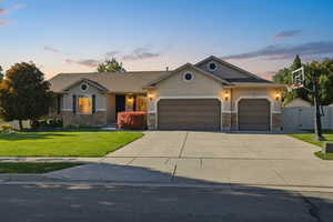View of front facade with stone siding, a front lawn, stucco siding, driveway, and an attached garage